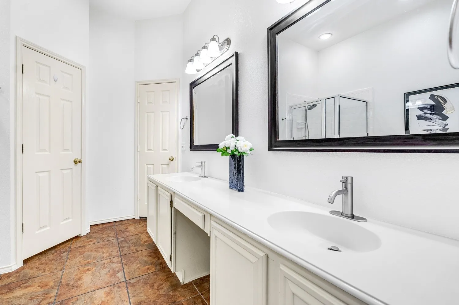 Spacious vanity area featuring dual integrated sinks, brushed nickel faucets, and framed mirrors