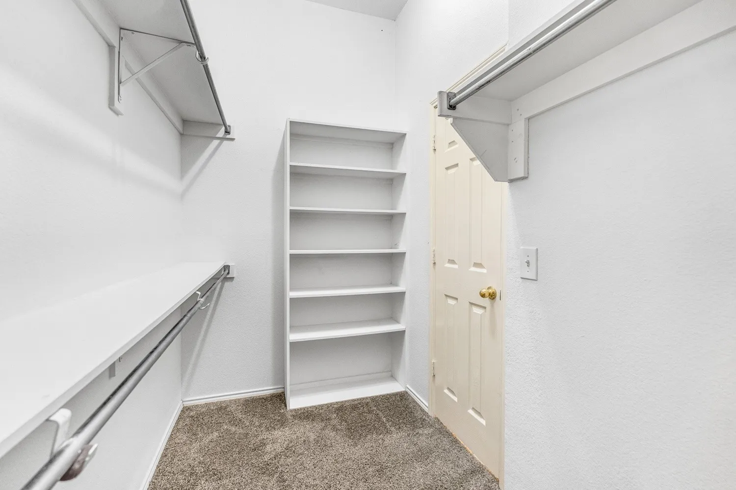 Walk-in closet featuring built-in shelving, dual hanging rods, and neutral carpet flooring