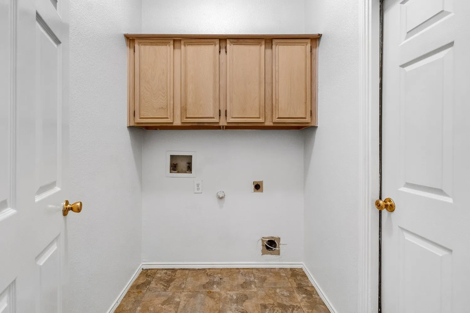 Dedicated utility space featuring light wood-finish cabinetry, a utility hookup box, and durable patterned flooring