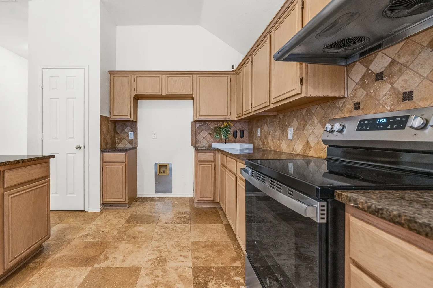 Kitchen featuring stainless steel range with ceramic cooktop, granite countertops, tile backsplash, and wood-finish cabinetry