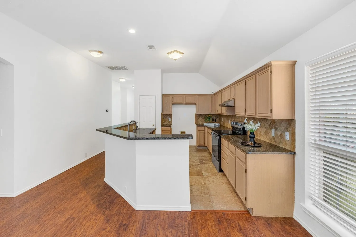 Kitchen featuring light wood cabinetry, stone-finish countertops, stainless steel appliances, and a tile backsplash