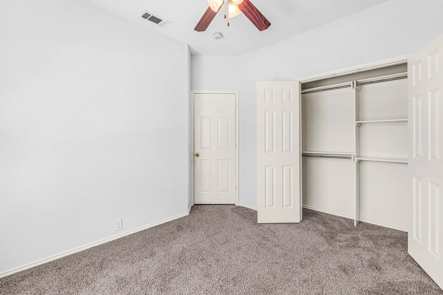 Carpeted room featuring a ceiling fan with wood-finish blades and light kit