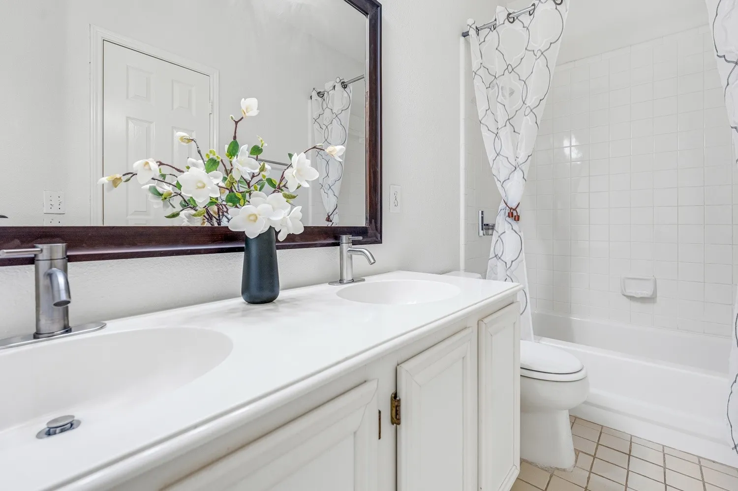 Dual basin vanity with white cabinetry, modern brushed nickel faucets, and a large wall-mounted mirror