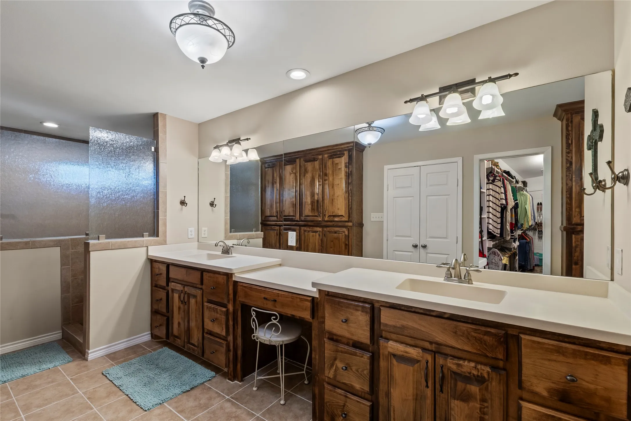 Primary bathroom with a walk in tile shower, walk in closet and abundant built in storage.