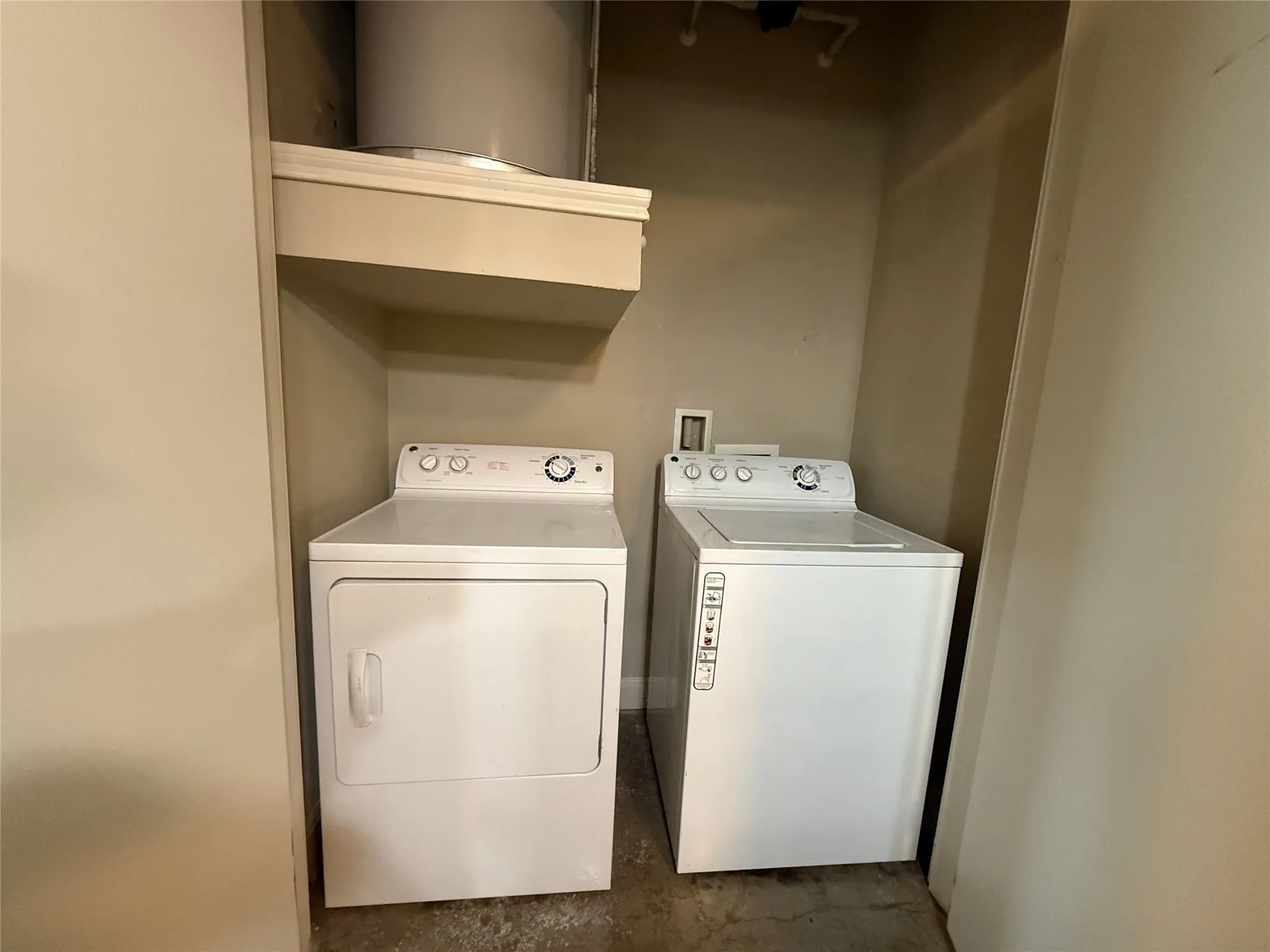 Dedicated laundry alcove with built-in shelving, accommodating a full-size washing machine and dryer
