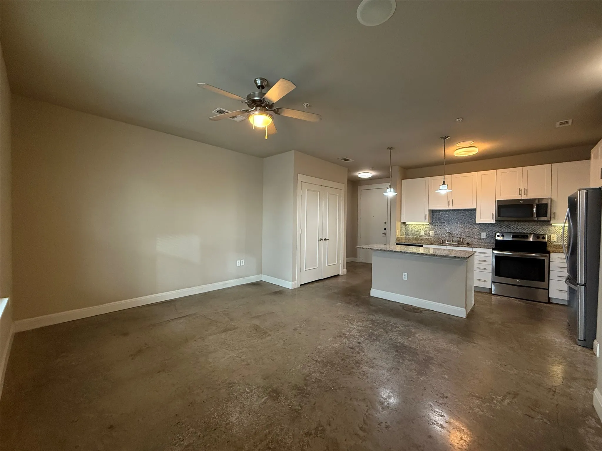 Open-concept living area featuring concrete flooring, a ceiling fan, and recessed lighting