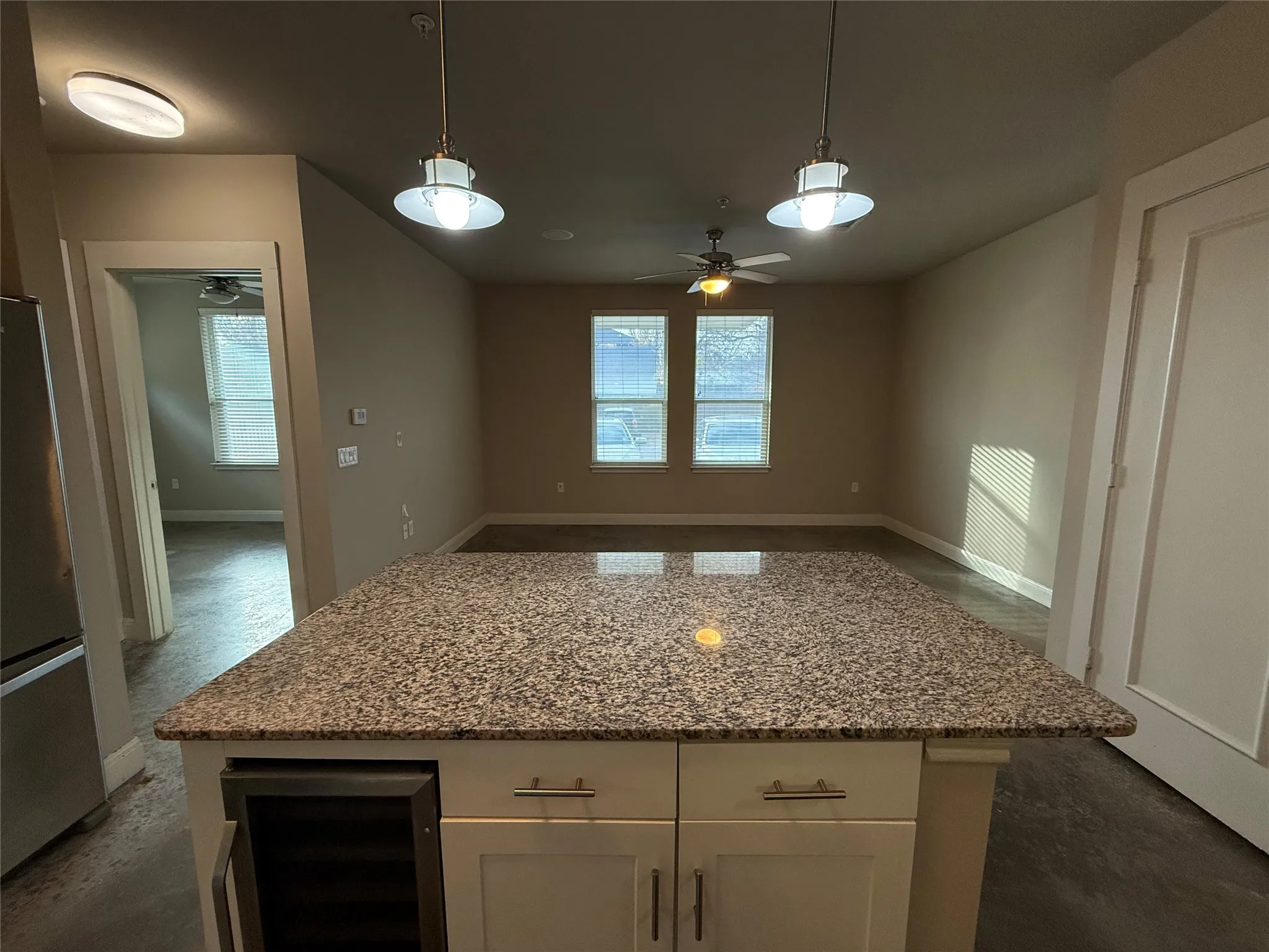 Kitchen island featuring a granite-style countertop, integrated beverage cooler, and white shaker-style cabinetry