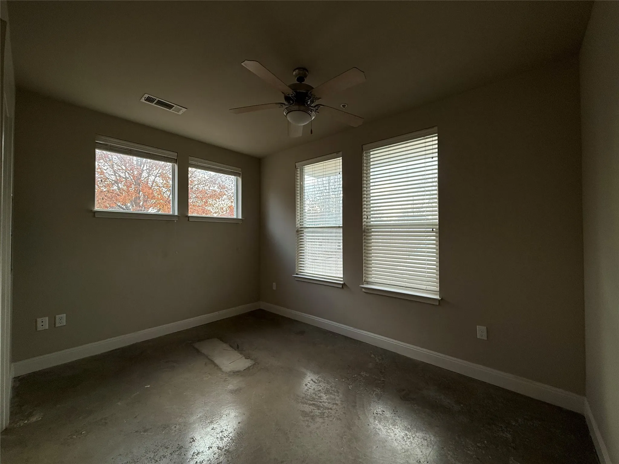 Room featuring multiple windows with blinds, a ceiling fan with integrated lighting, and neutral-toned walls