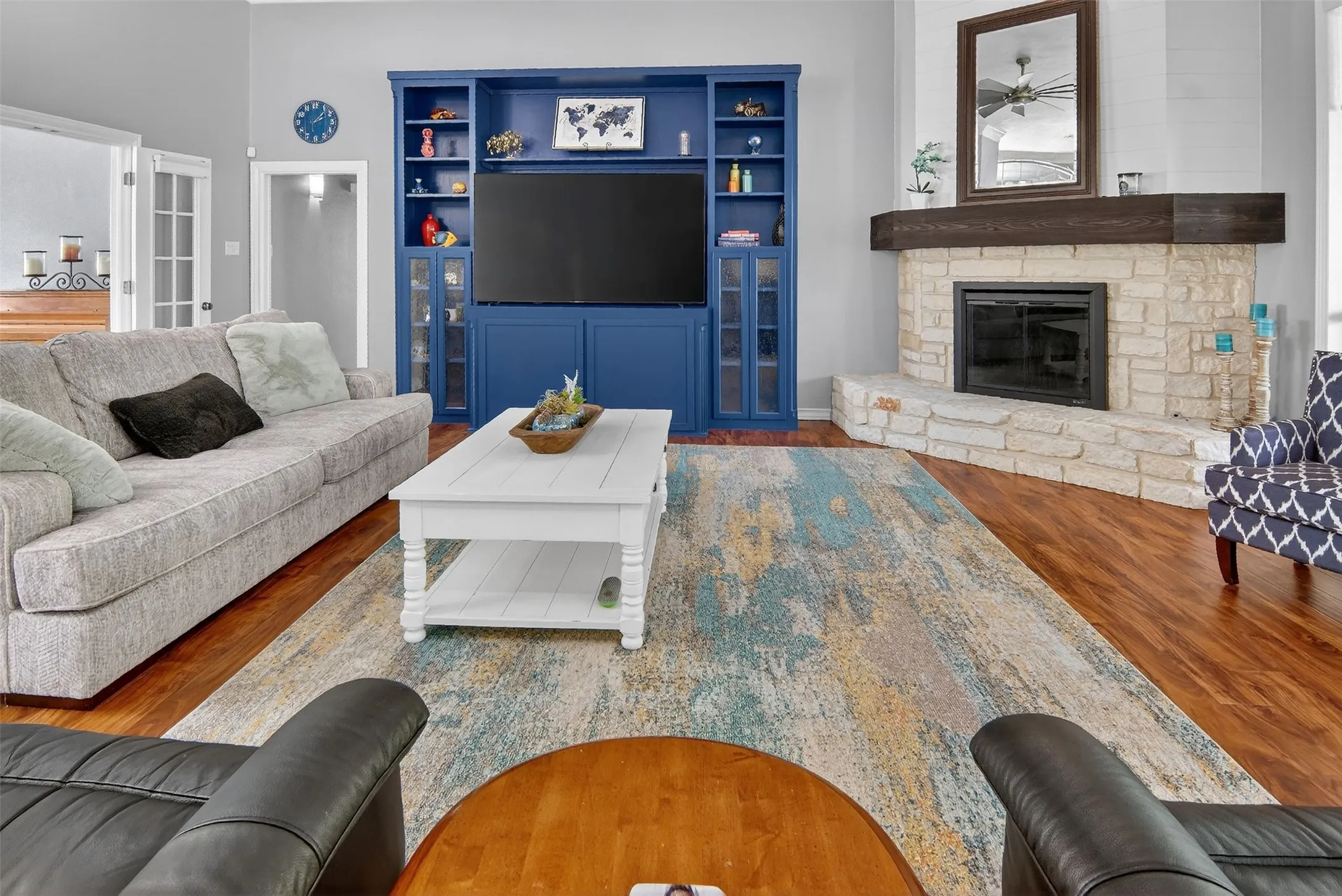Built-in cabinetry and large, wood-burning, fireplace with gas starter, glass front, raised hearth, and heavy wood mantle.