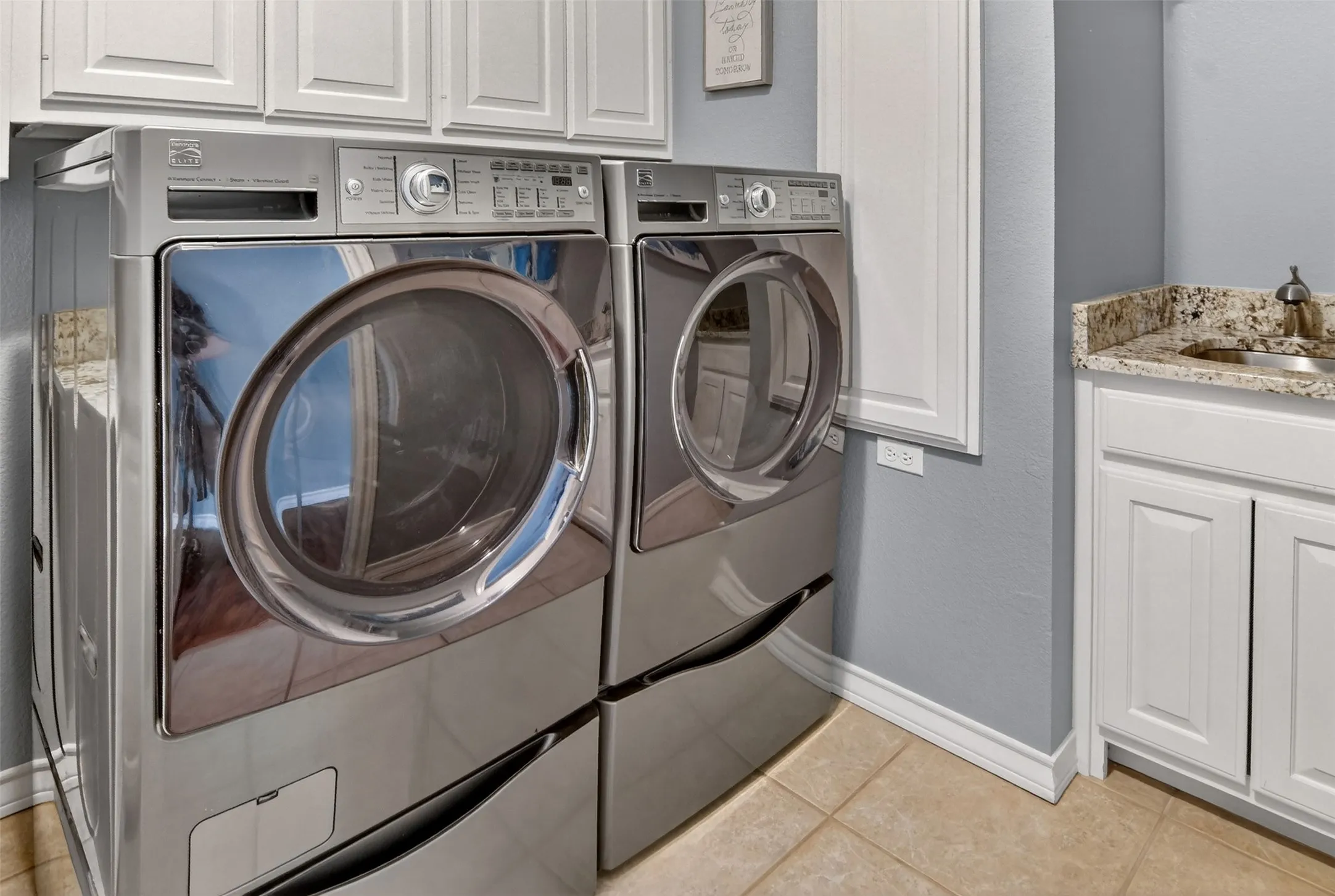 Laundry room with built-in cabinets, shelves, fold-out ironing board, and a sink.