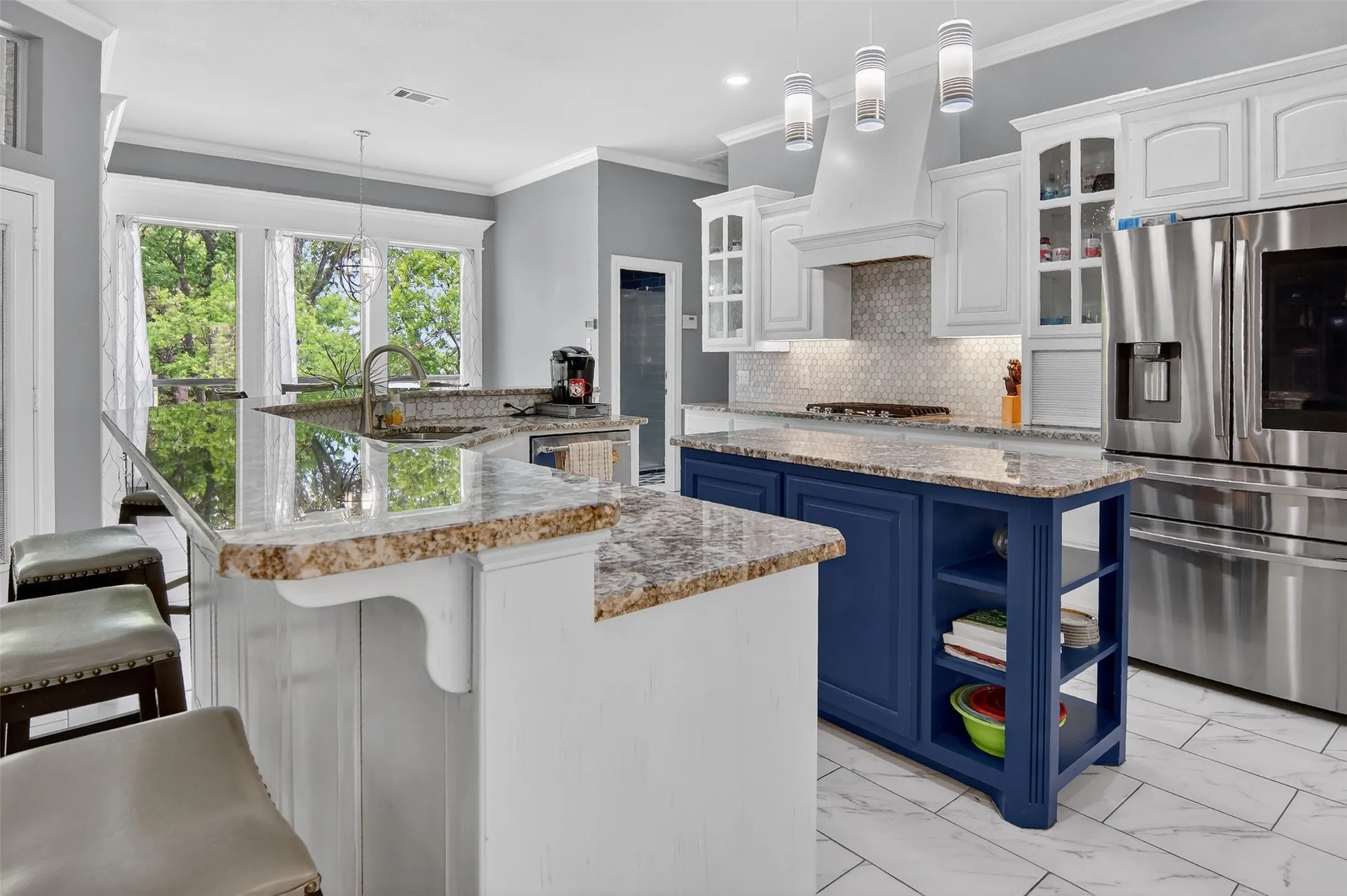 Beautiful, open kitchen with breakfast bar, appliance garage, and decorative lighting.