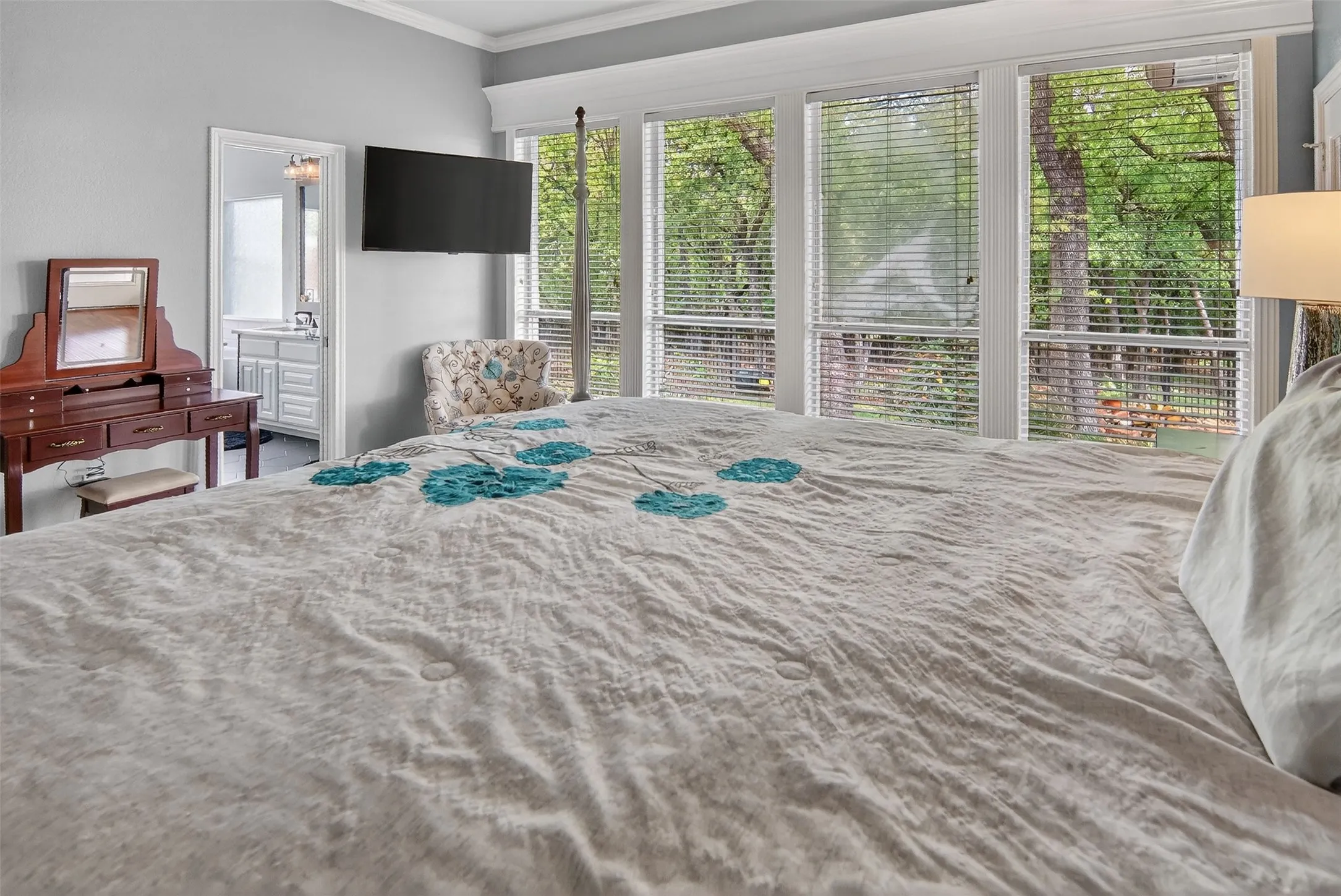 Large primary bedroom with a wall of windows overlooking lovely backyard.