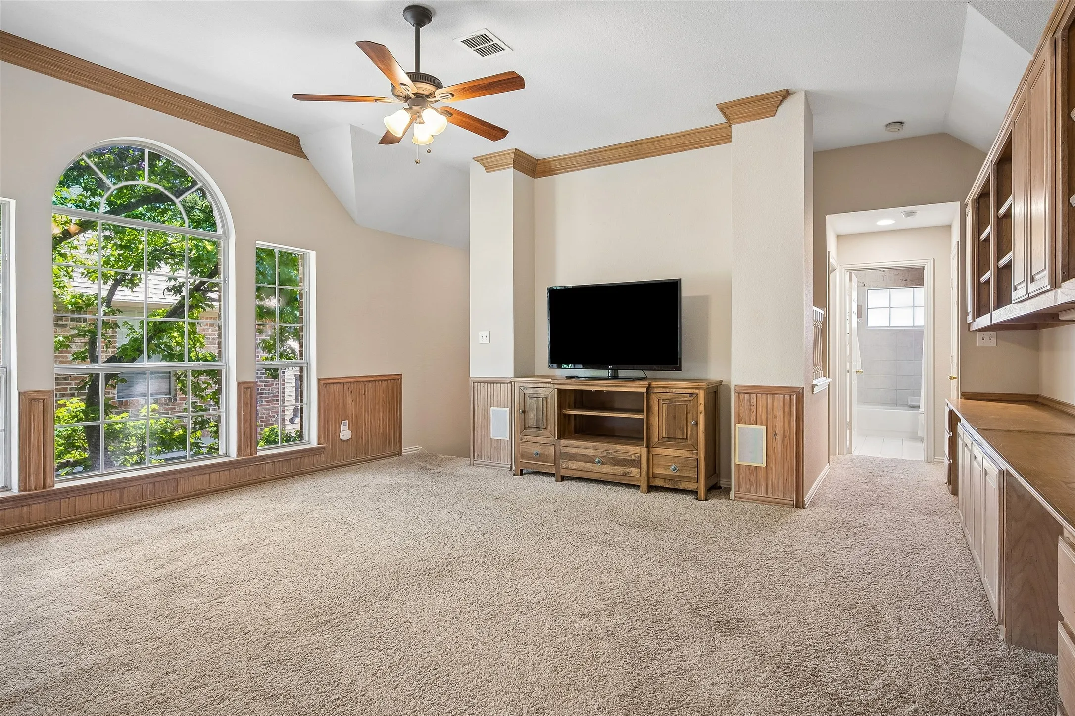 Game room with wall of windows, ceiling fan, wood chair rail and many built-ins.