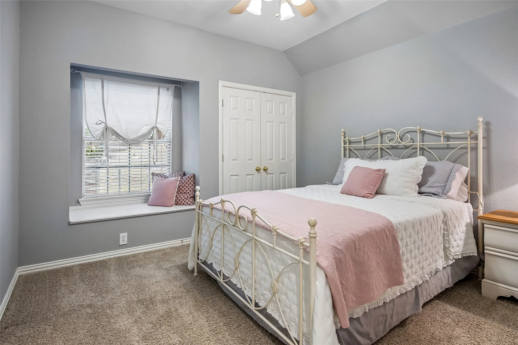 Secondary bedroom with window seat and ceiling fan.