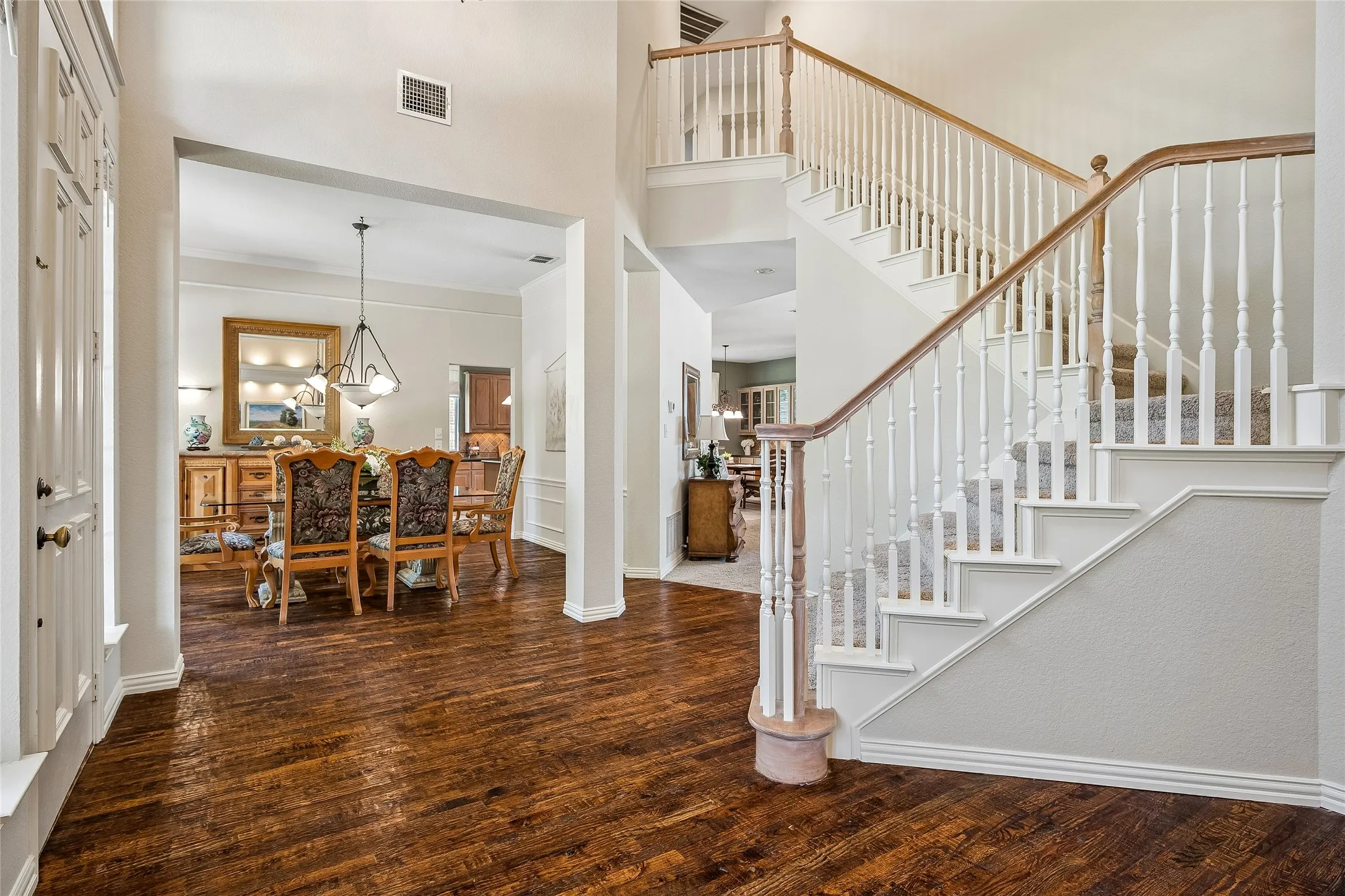 Entry with view of dramatic staircase and formal dining room.