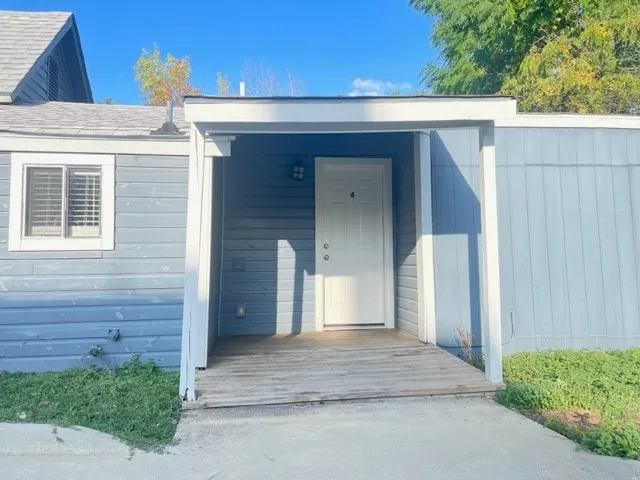 Entryway featuring a white door with visible numbering, covered porch, and light blue siding