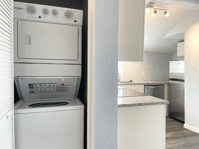 Compact laundry closet featuring a white stackable washer and dryer