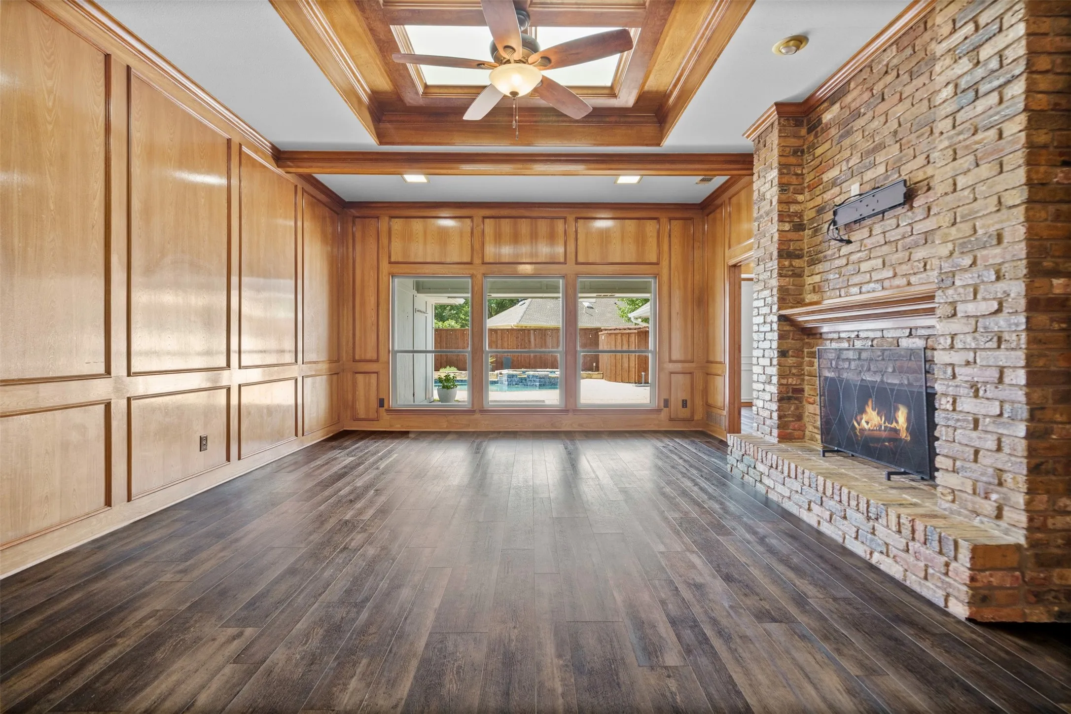 Oversized living room with built ins and a fireplace looking out to the pool