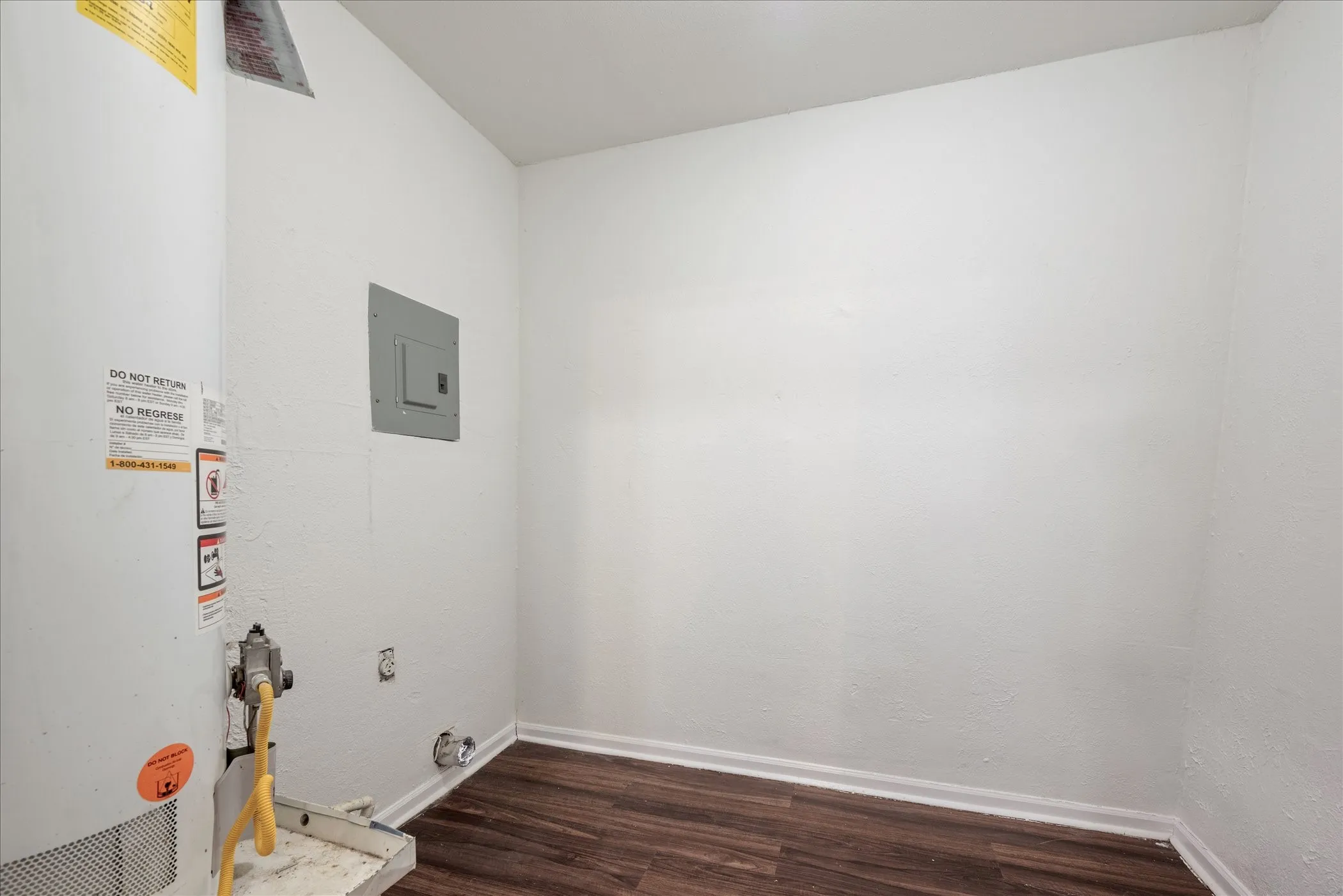 Utility area with wood-finish flooring, white walls, and a visible electrical panel