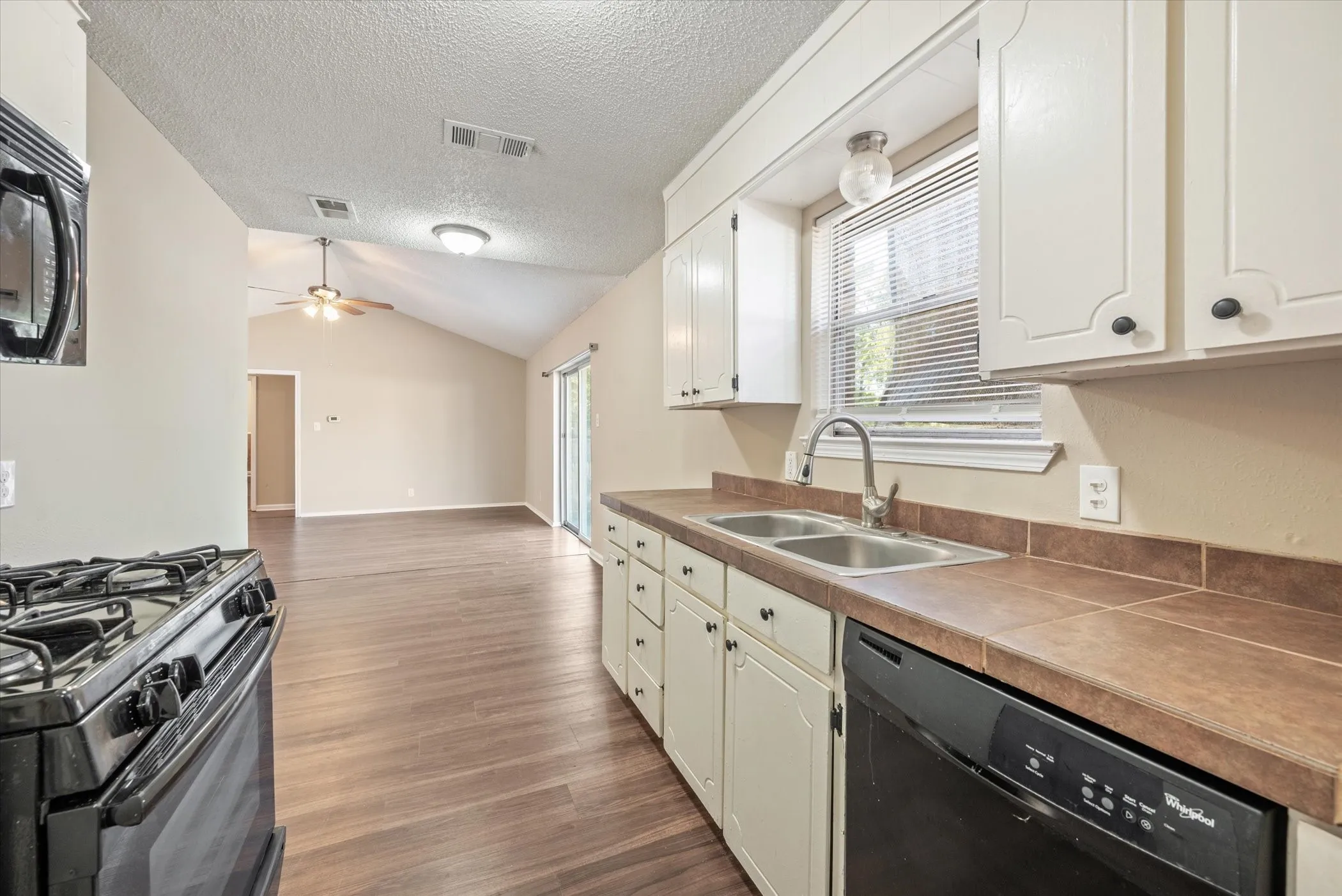 Kitchen featuring white cabinetry, tile countertops, and a double basin sink