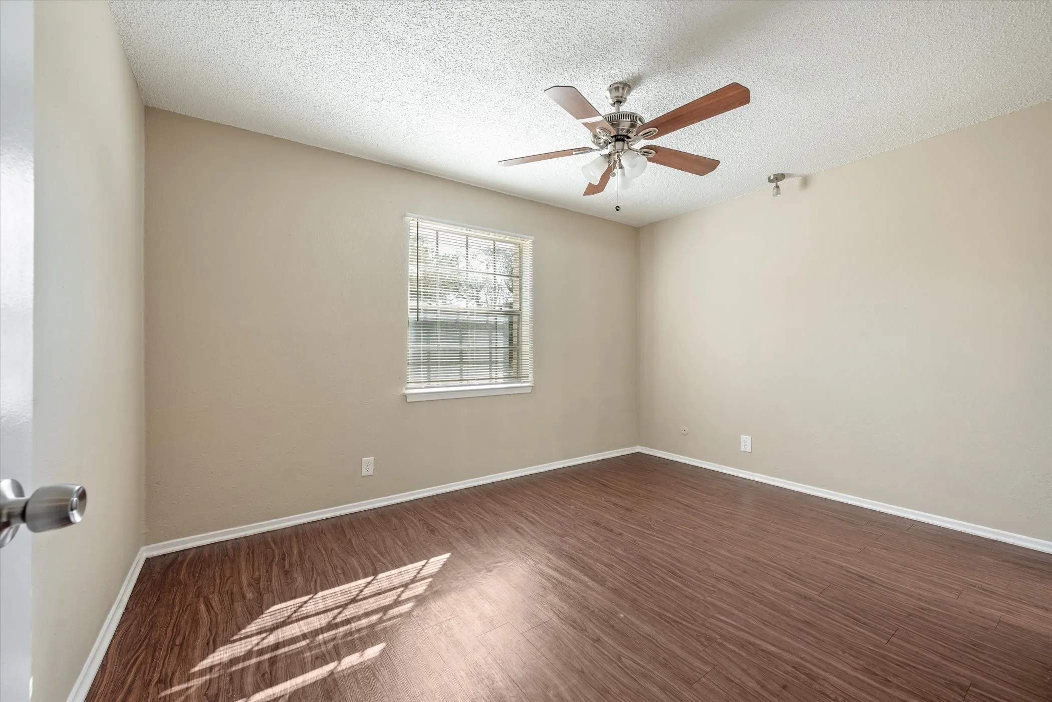 Room featuring wood-finish flooring, neutral wall paint, and a textured ceiling