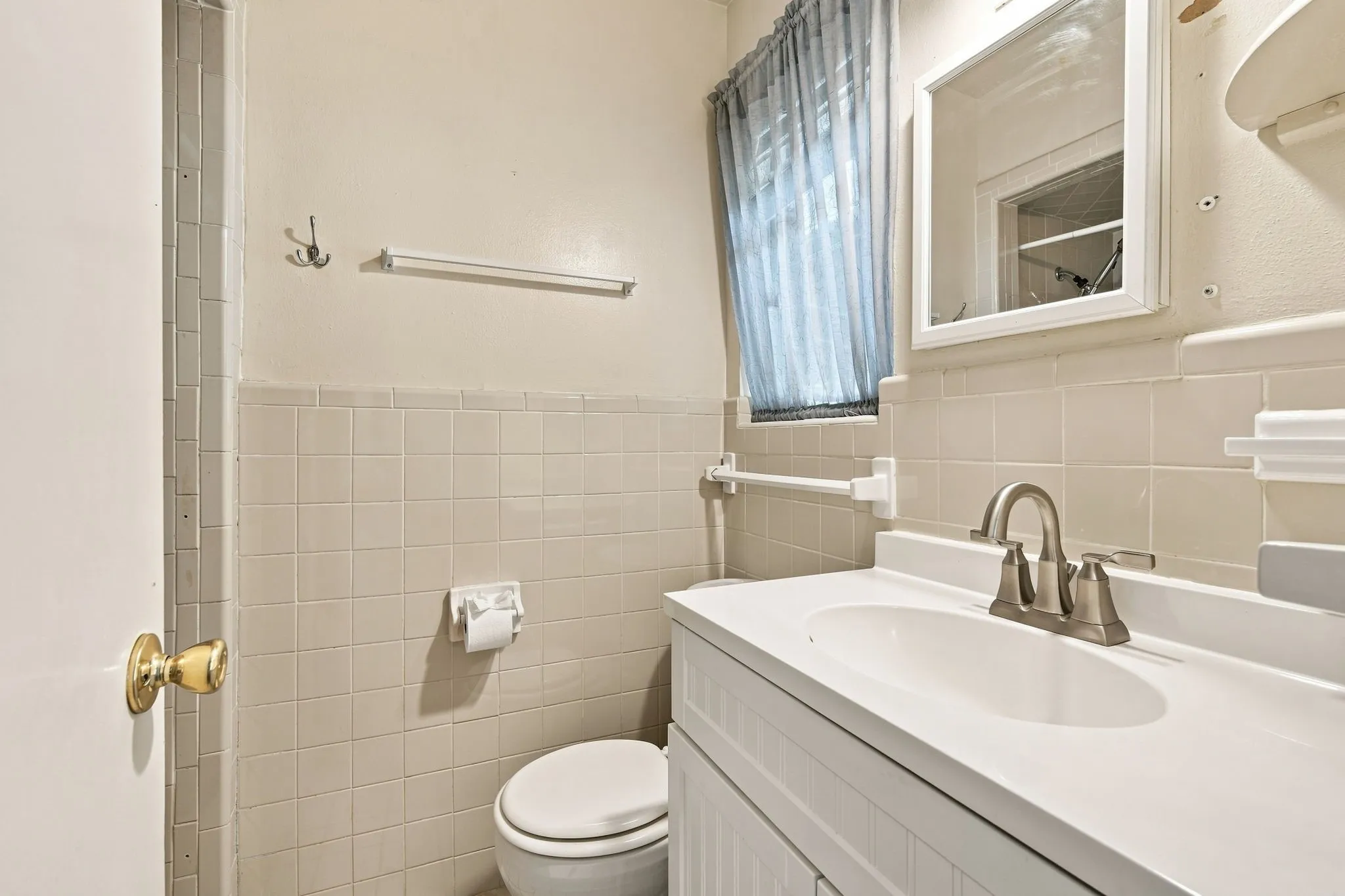 Bathroom featuring a white vanity with an integrated sink, brushed nickel faucet, and a wall-mounted mirror