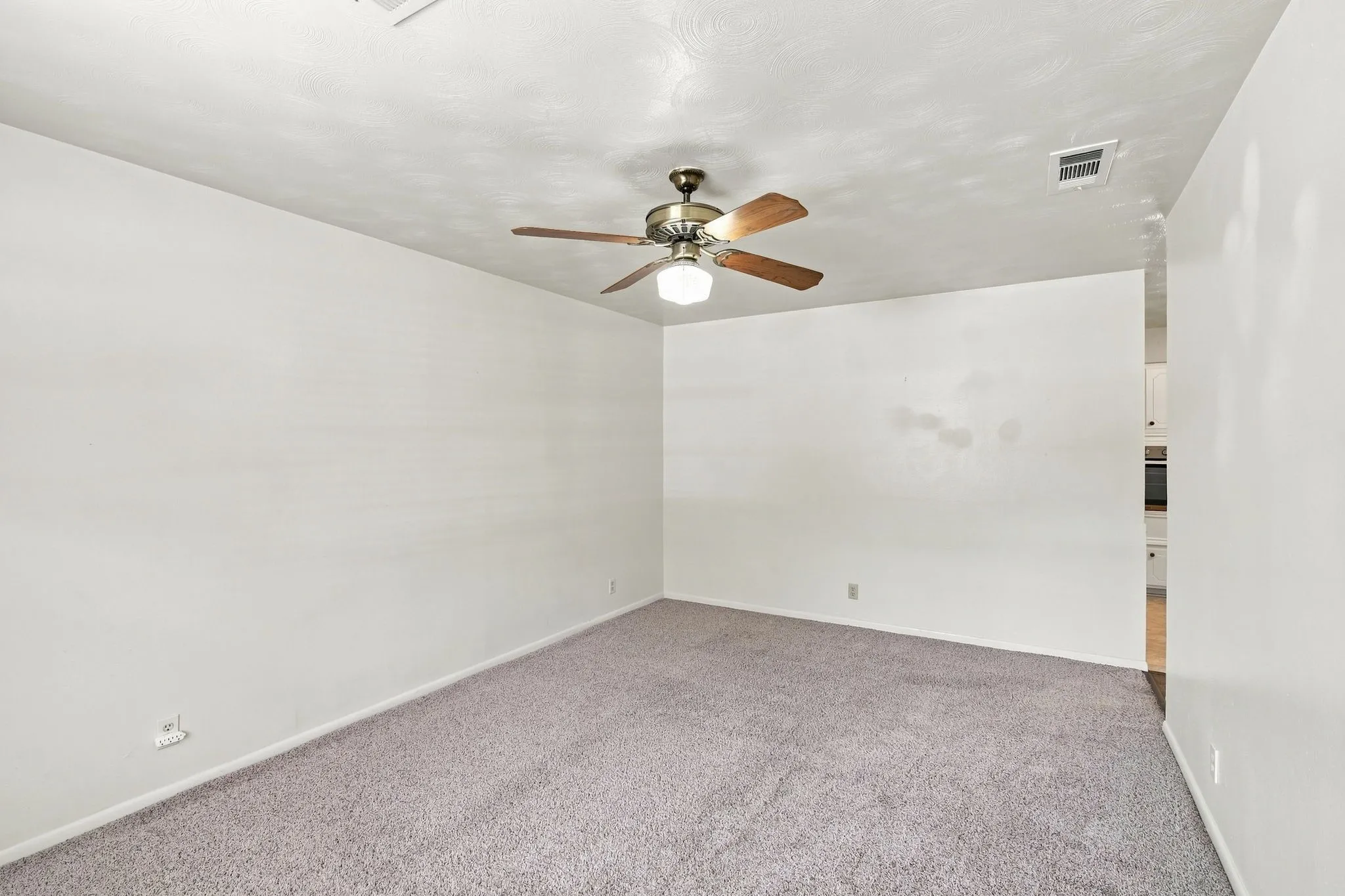 Spacious room featuring neutral carpeting, a ceiling fan with integrated lighting, and white painted walls