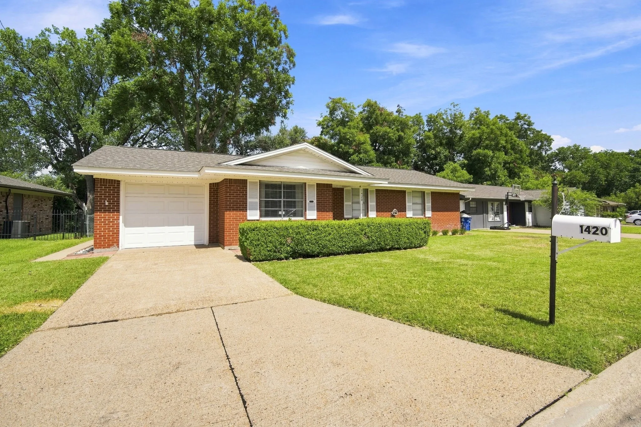 Brick exterior with white trim, featuring a single-car garage and a concrete driveway