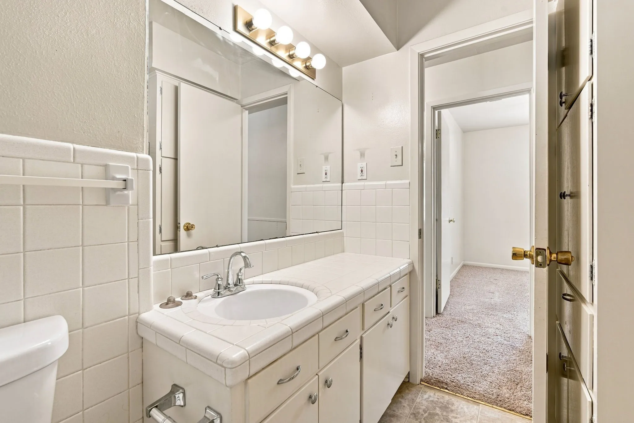 Bathroom vanity with integrated sink, chrome faucet, and tile countertop