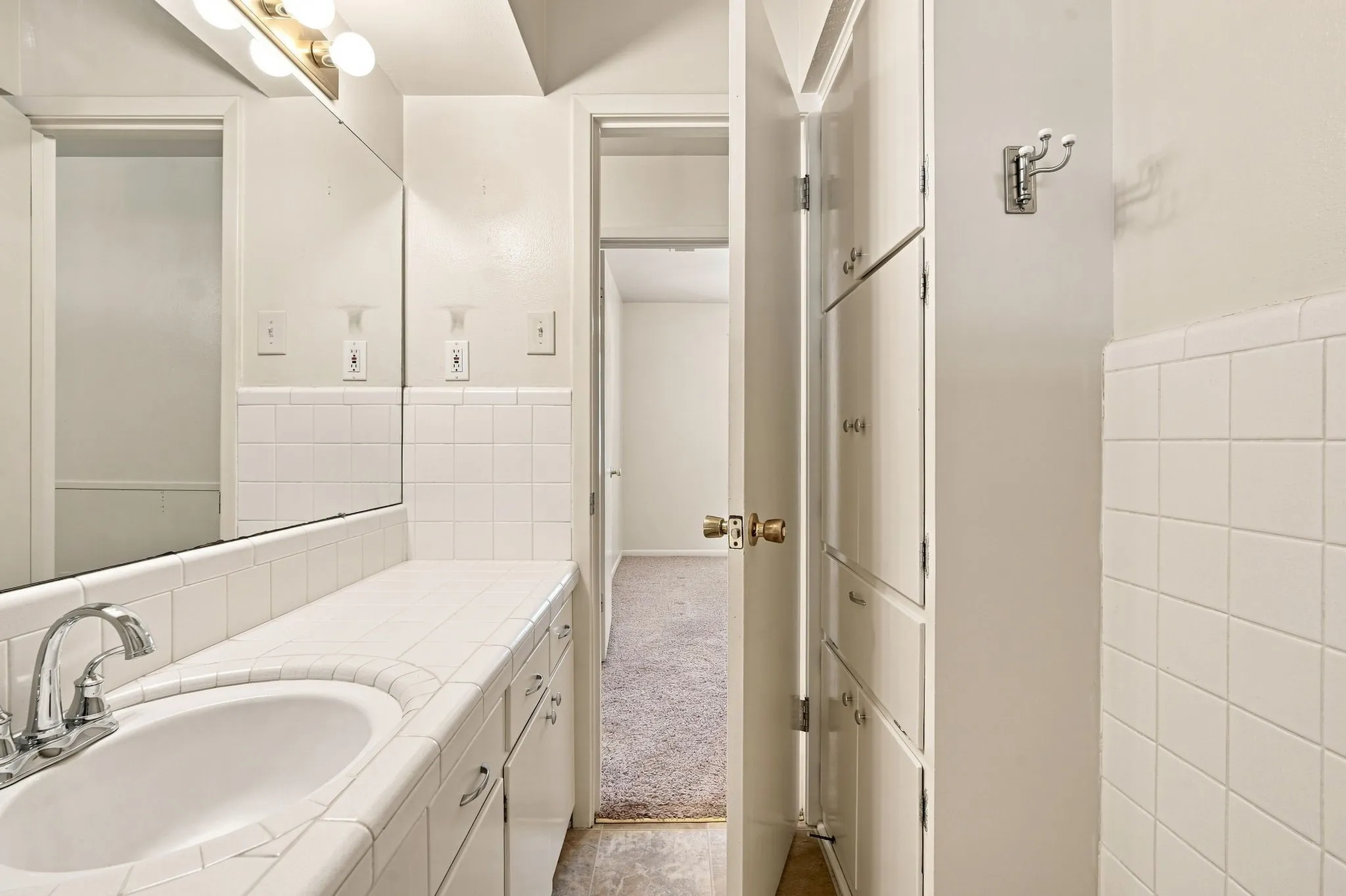Bathroom vanity featuring an integrated sink, tile countertop, and matching tiled wainscoting