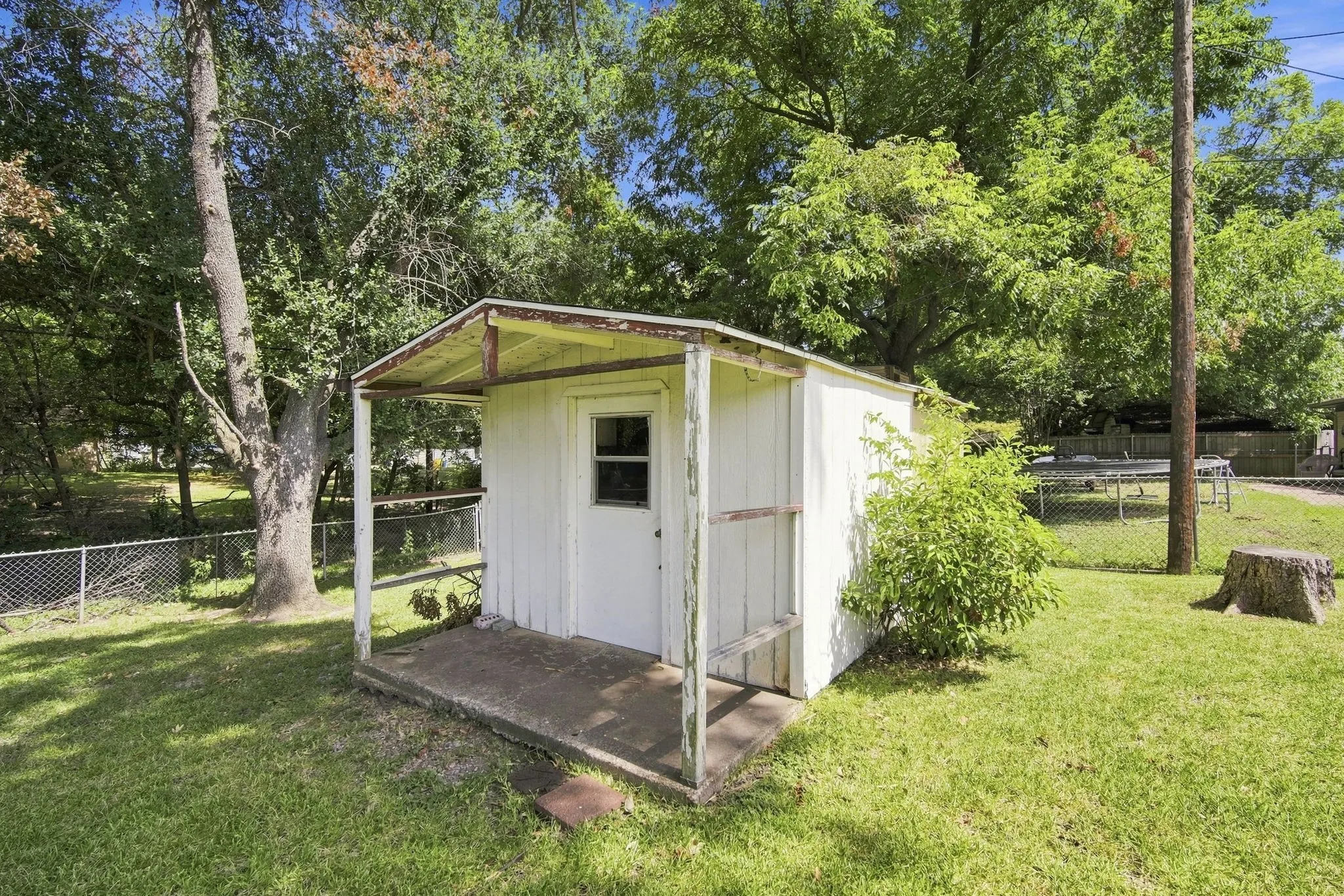 Detached storage shed featuring a small window and covered porch