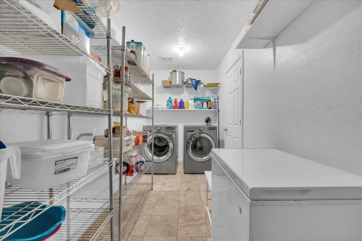 Laundry area with tile flooring and multiple shelving units