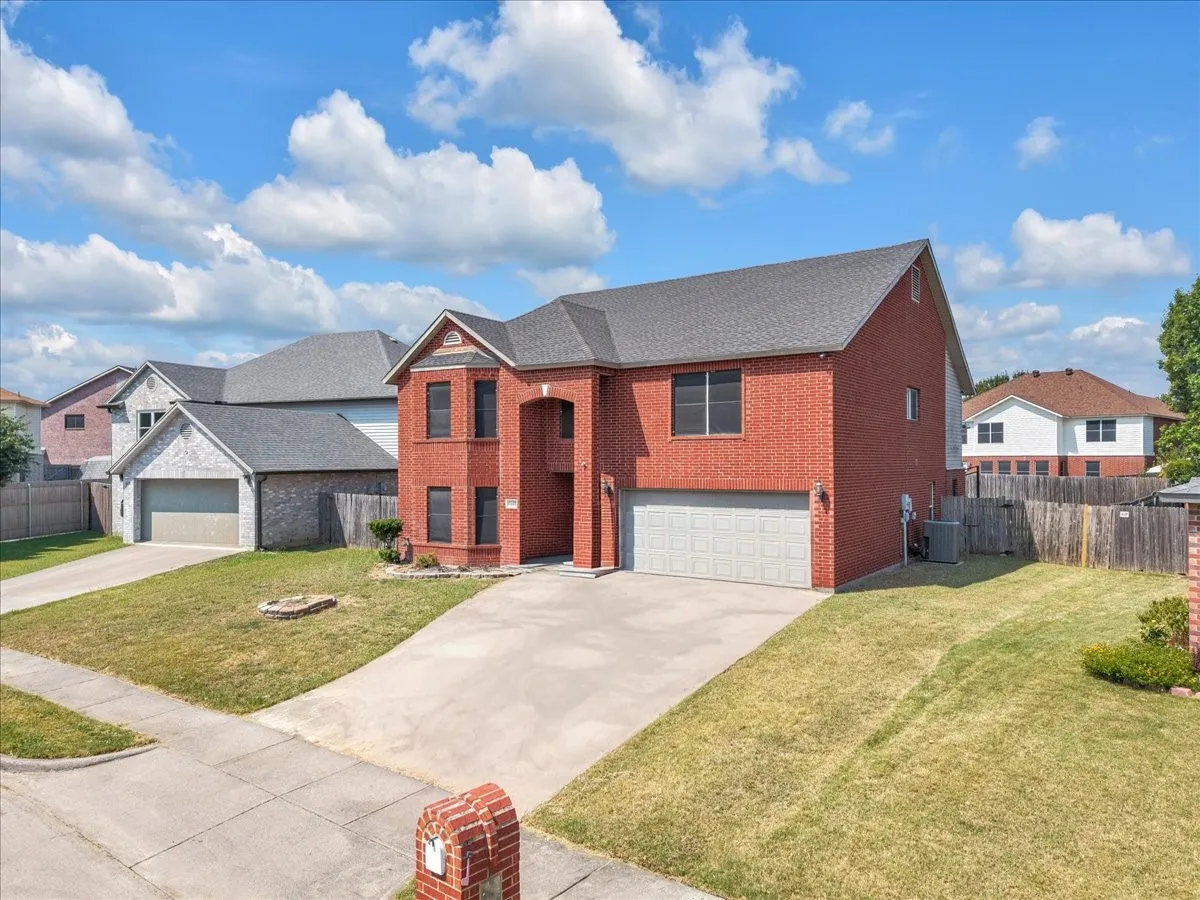 Red brick exterior with a two-car garage, concrete driveway, and a mailbox with brick detailing