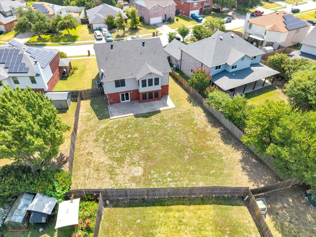 Expansive backyard featuring a partial privacy fence, concrete patio, and mature perimeter trees