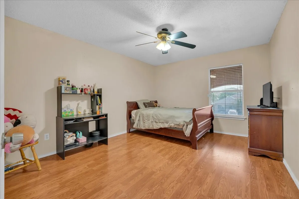 Wood-finish flooring with a ceiling fan light fixture and a window with blinds