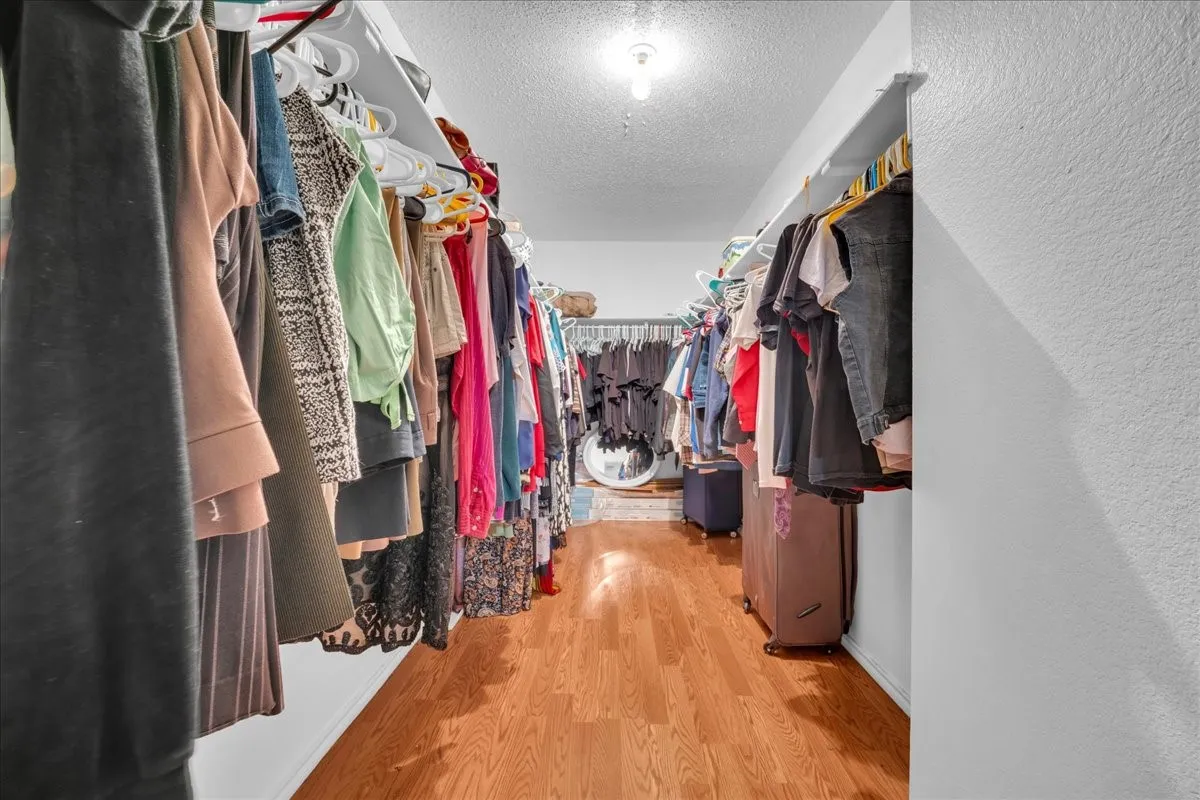 Walk-in closet featuring wood-finish flooring and built-in shelving