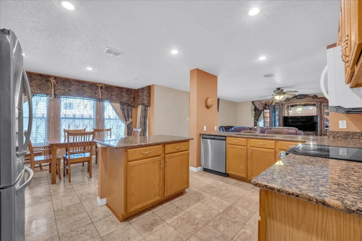 Kitchen with an island, granite countertops, tile flooring, and recessed lighting