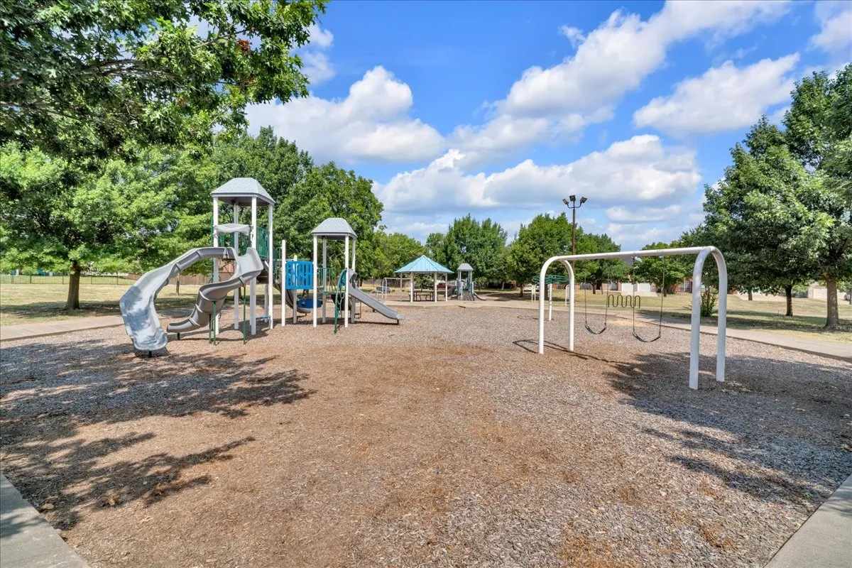 Outdoor play area featuring multiple slides, a swing set, and a covered structure
