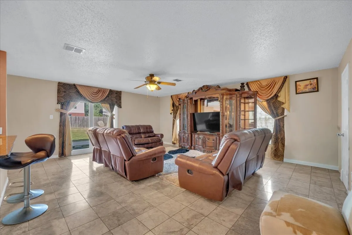 Tile flooring, ceiling fan with integrated lighting, and sliding glass doors providing access to the rear yard