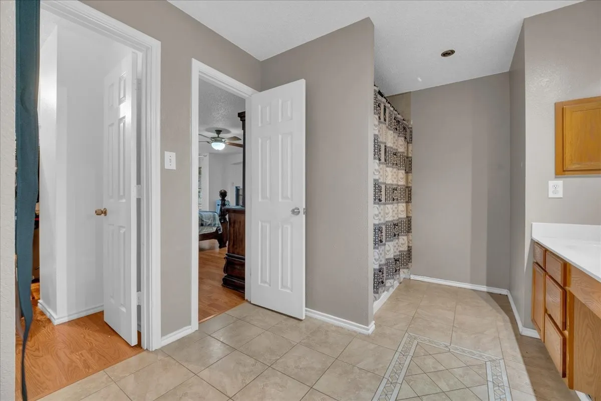 Tile flooring with decorative inlay, wood-finish vanity with countertop, and neutral paint tones