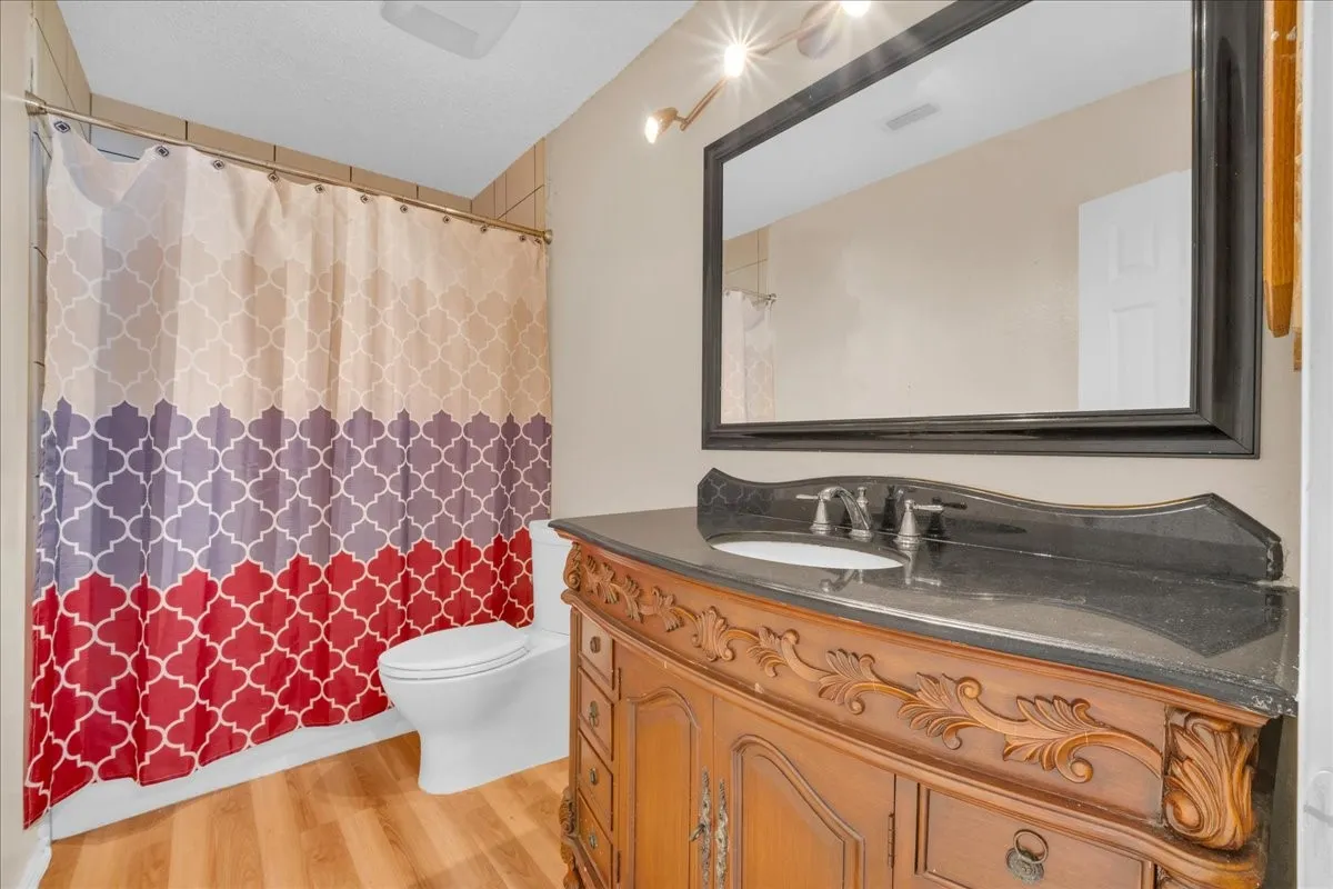 Ornate carved wood vanity with a black countertop and an undermount sink