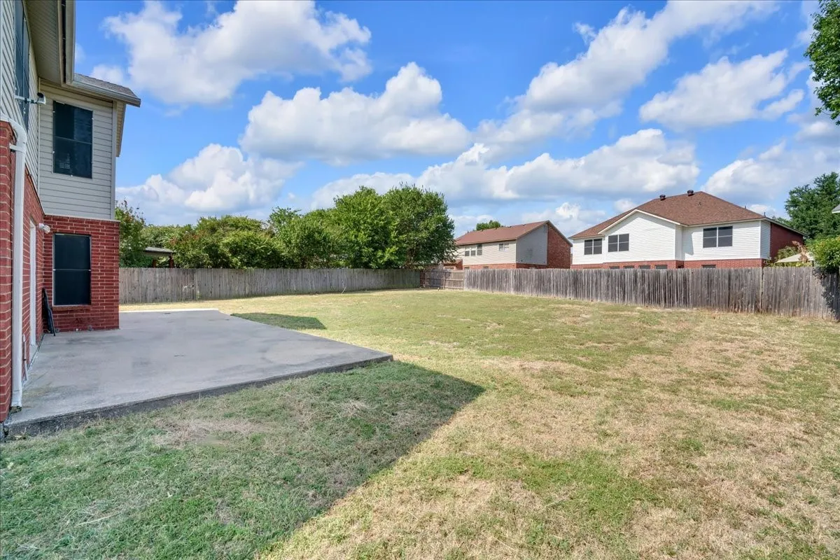 Expansive grass area with a privacy fence and a concrete patio