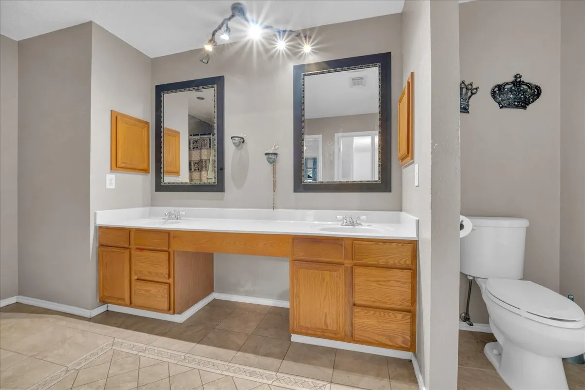 Dual vanity with light wood cabinetry, white countertops, and framed mirrors