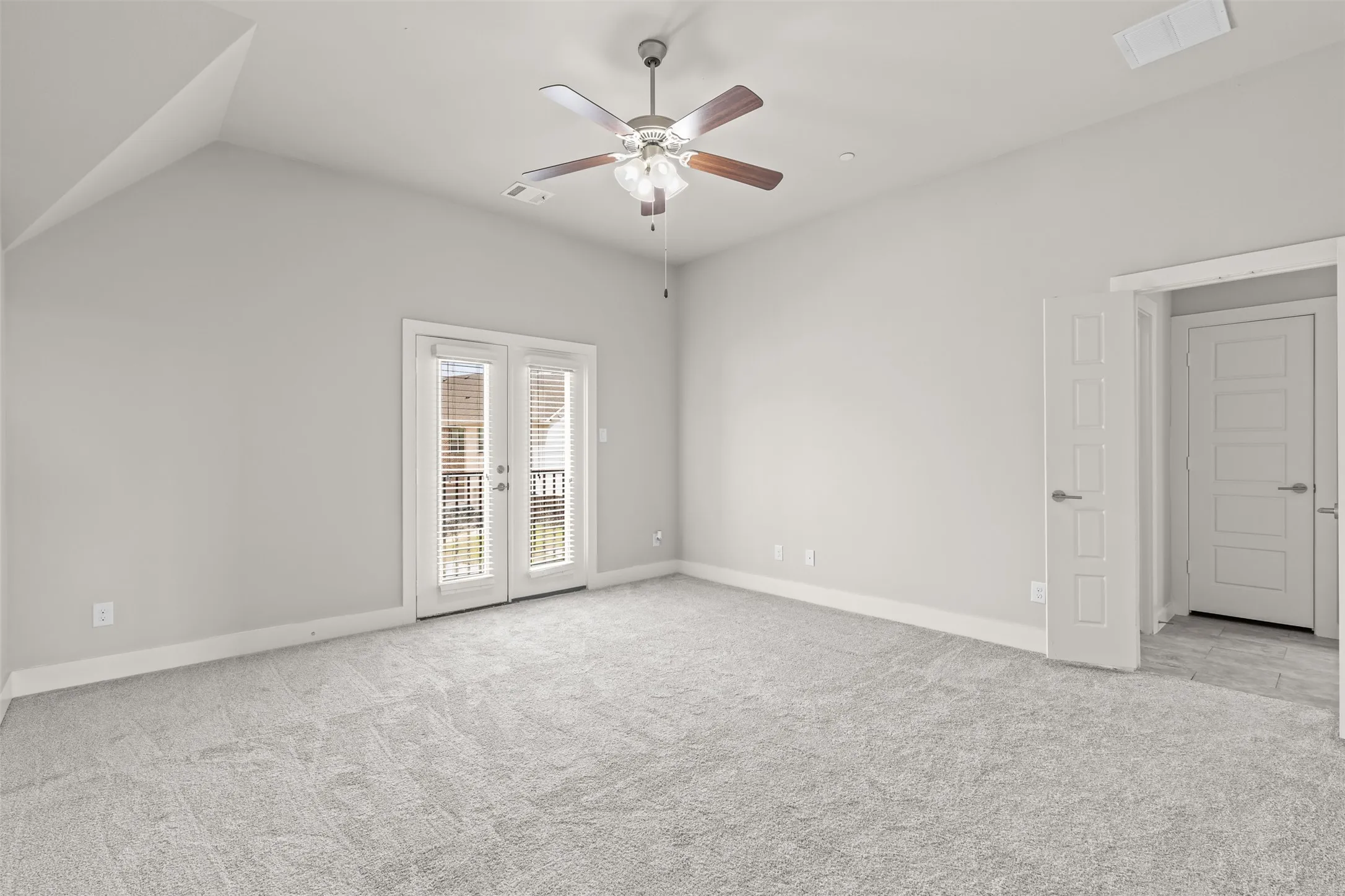 Primary bedroom features French doors leading to mini-balcony