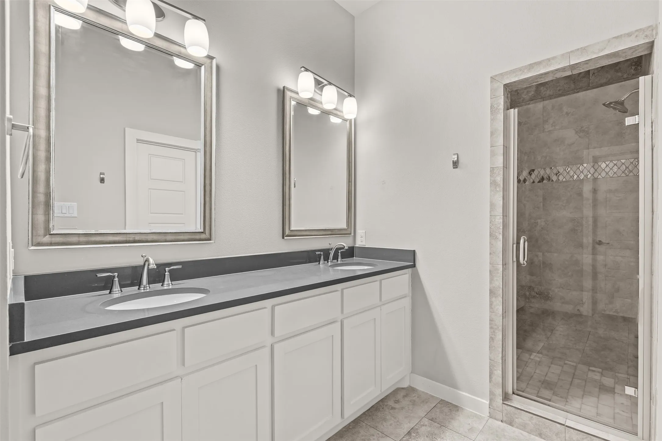 En suite primary bath features dual sinks and quartz countertops