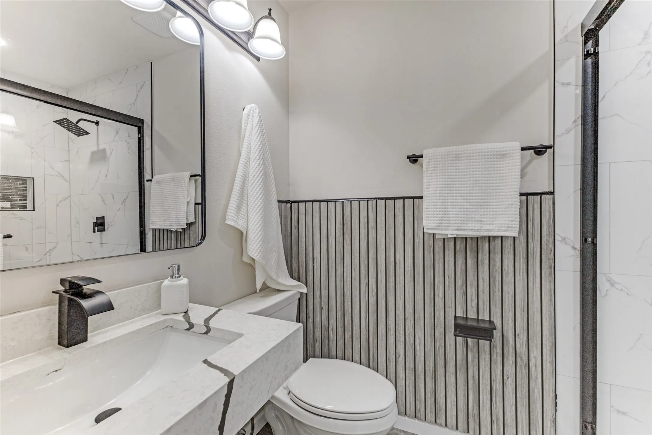 Bathroom featuring a vanity with an integrated rectangular sink, a matte black faucet, and a large wall mirror