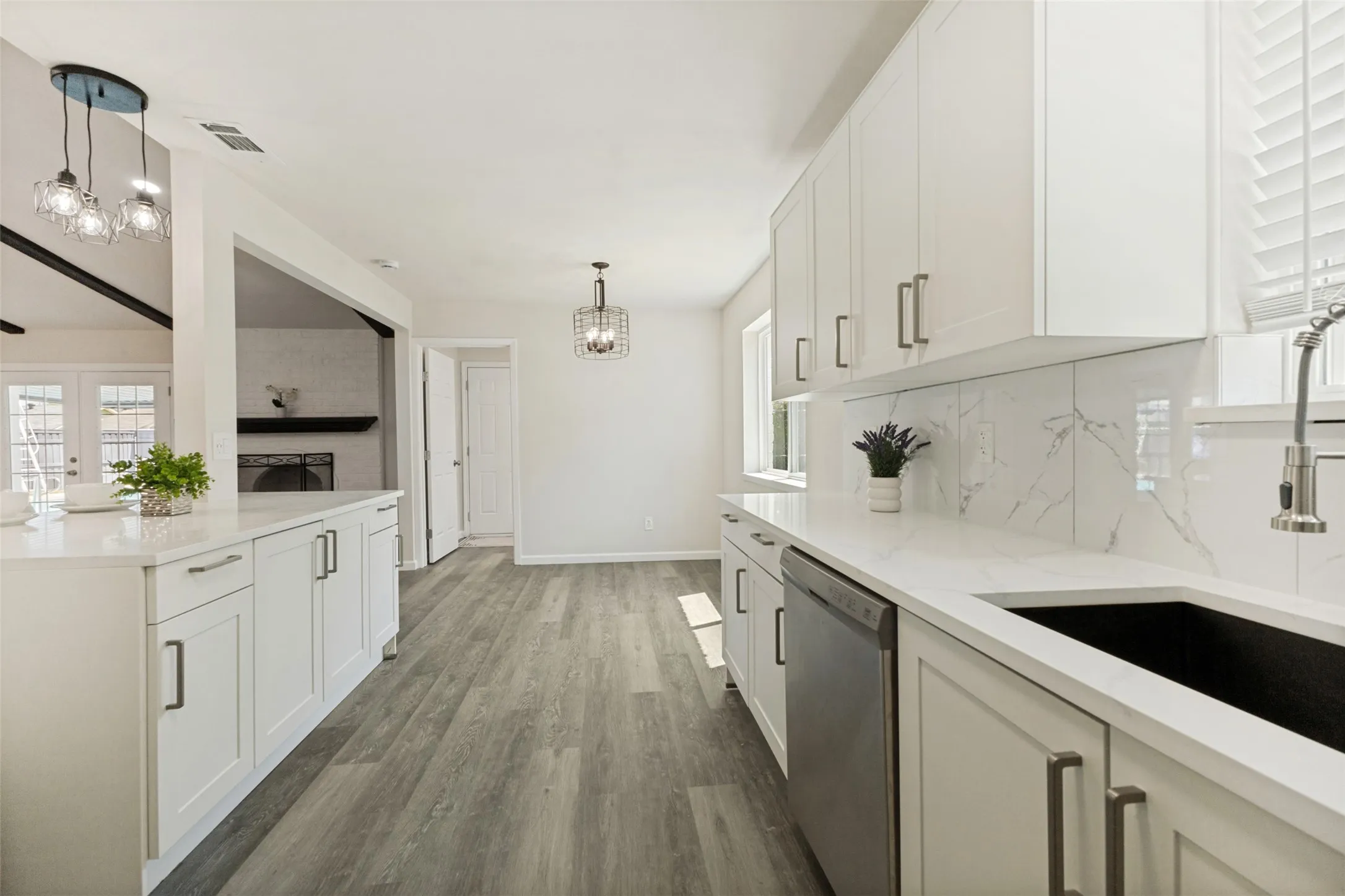 Modern kitchen featuring white shaker cabinetry, light-toned countertops, and wood-finish flooring