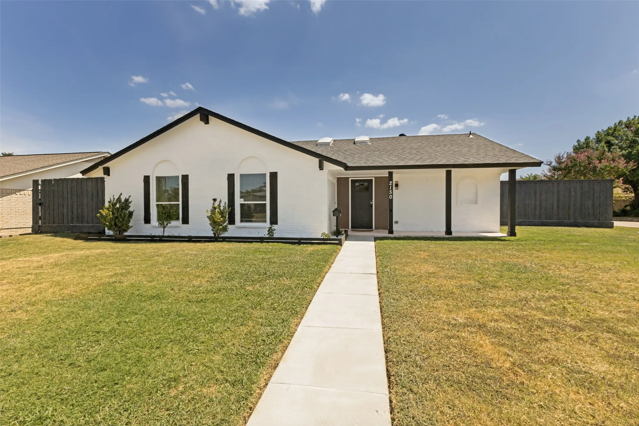 White stucco exterior with black trim and a dark gray shingle roof