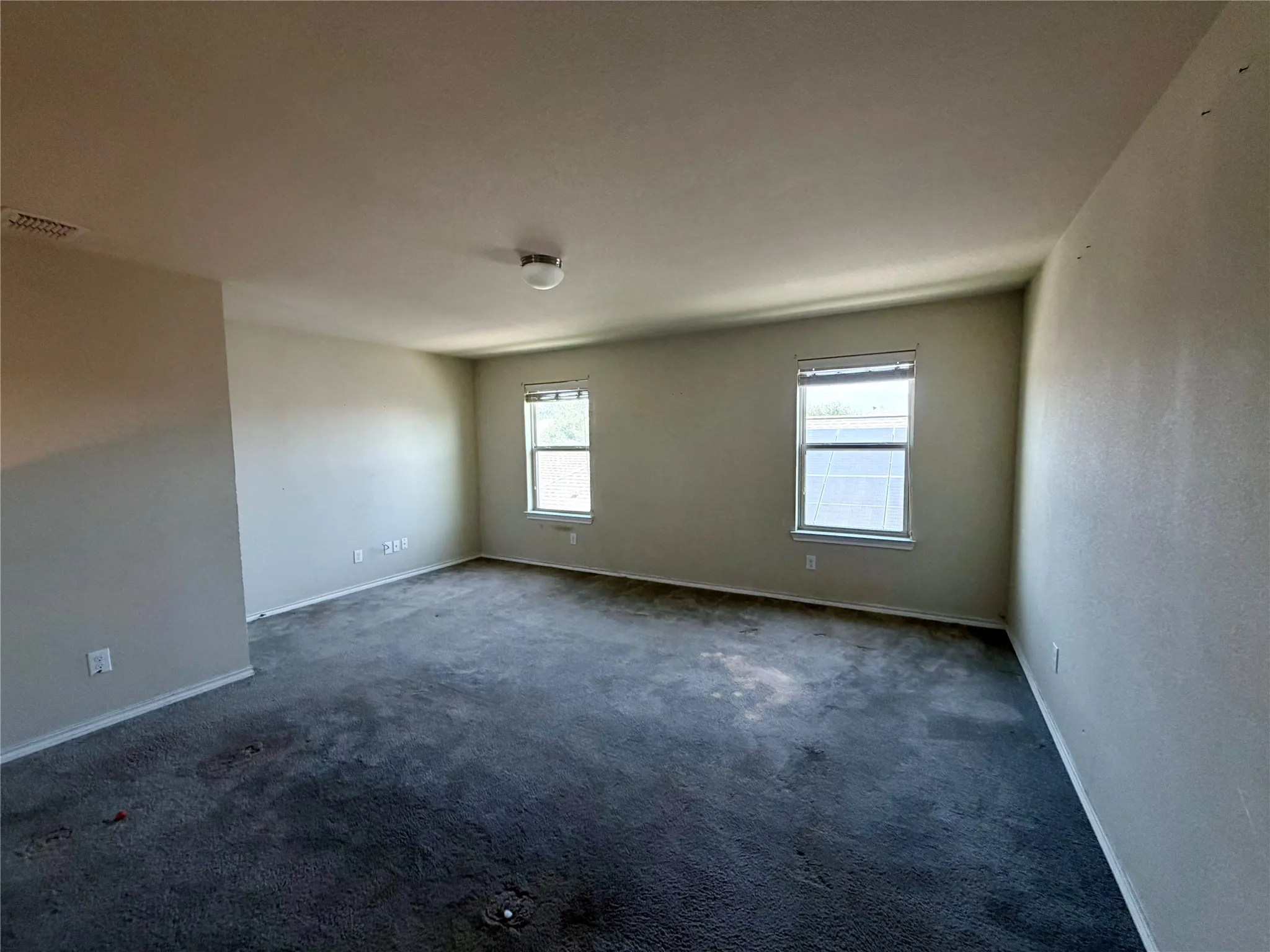 Primtwo rectangular windows with white blinds, and a flush-mount ceiling light fixture