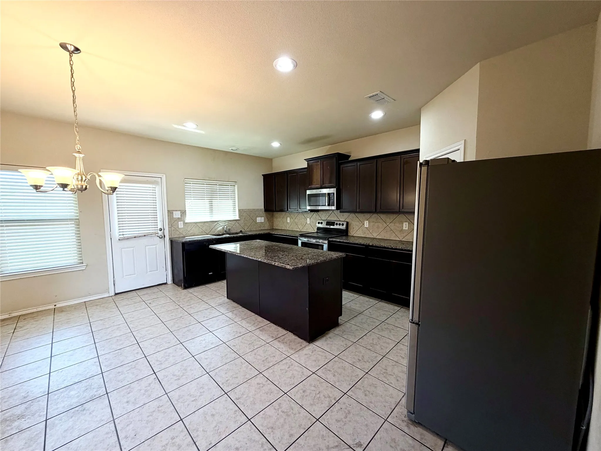 Kitchen featuring dark wood cabinetry, a central island with a stone countertop, and tile flooring